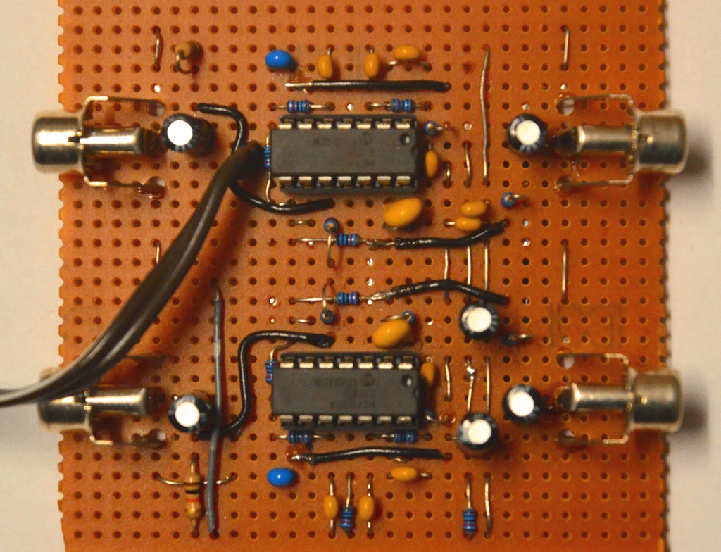 A photograph of the ICs in DIL-14 package on perfboard with capacitors and resistors and 4 RCA connectors, two on the left side and two on the right side of the board.