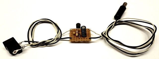 Photo of a small perfboard circuit with short coils if wire attached to it on either side.